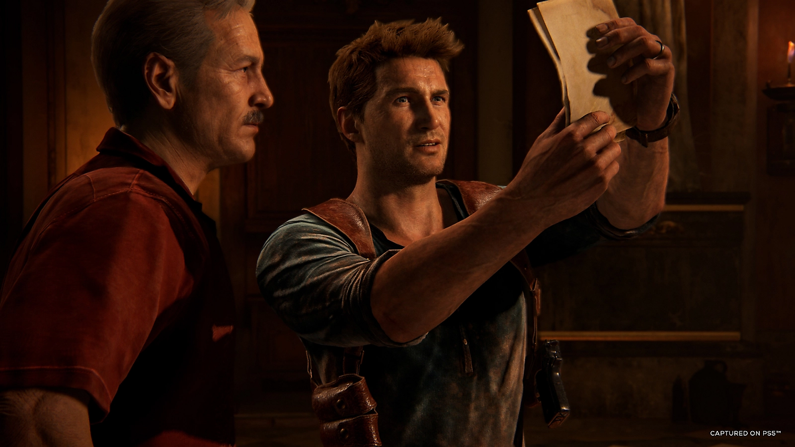 Nathan Drake hanging off a crumbling stone structure in a cinematic action sequence from UNCHARTED